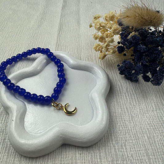 bracelet bleu en pierres naturelles et breloque en lune doré sur un port bijou blanc